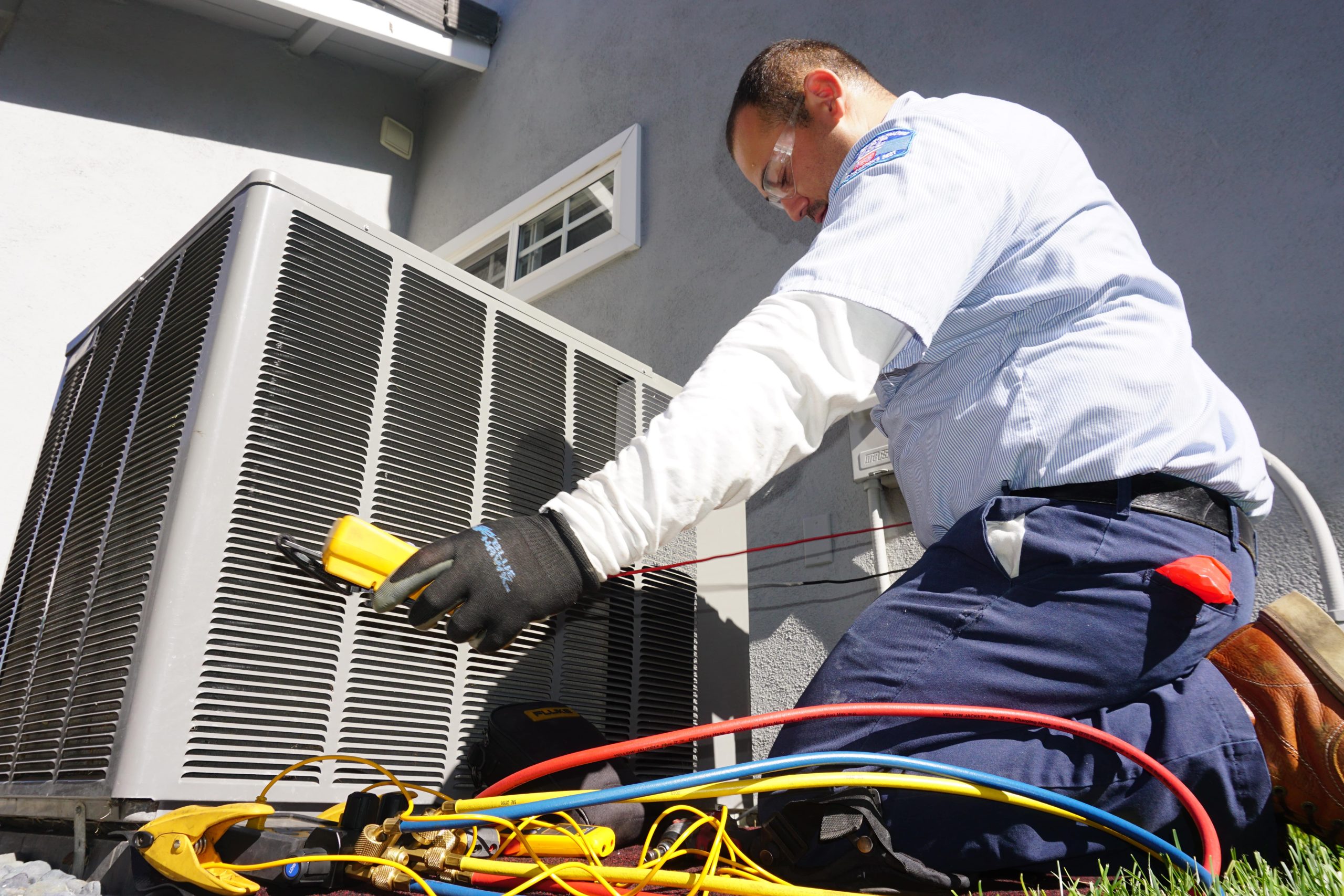 An HVAC technician inspecting an outdoor A/C unit