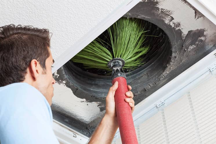 Technician cleaning air duct